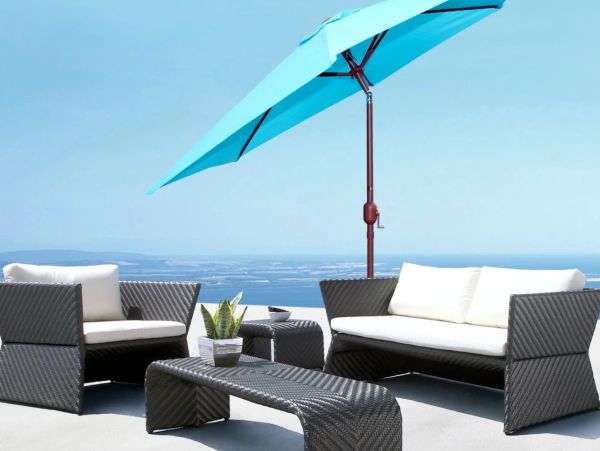 Modern outdoor patio furniture with a blue umbrella and ocean view.