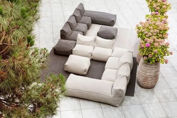 Modern outdoor sectional sofa with contrasting cushions on a tiled patio.