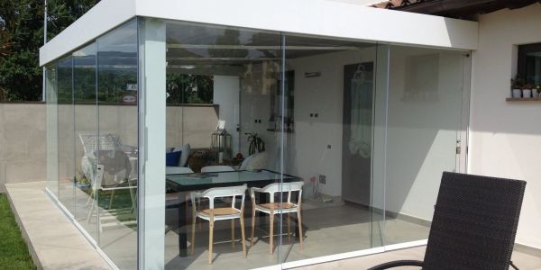Modern glass-enclosed patio with outdoor seating and dining area.
