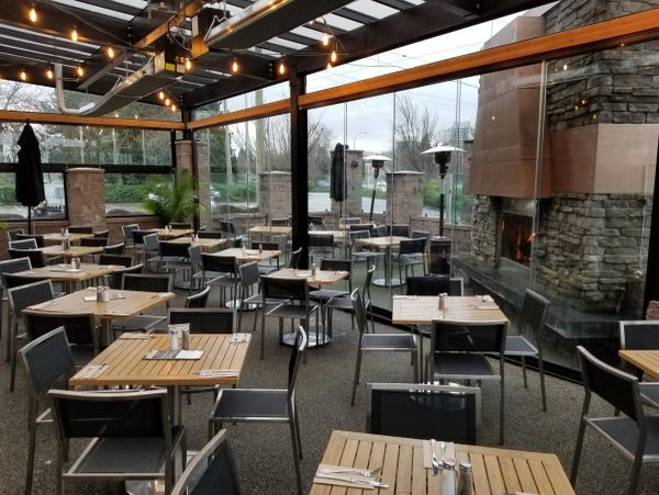 Empty outdoor dining area with wooden tables and string lights.