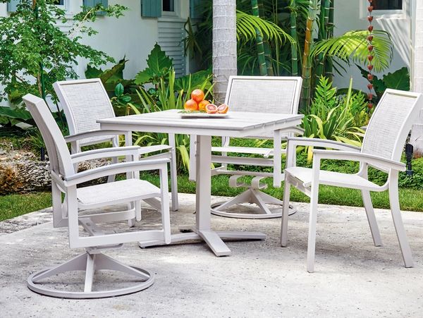 Outdoor white patio set with four chairs and a table with fruit.