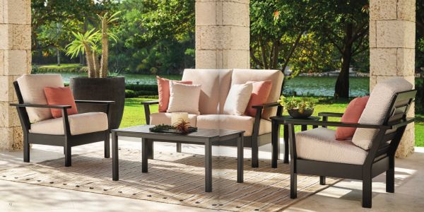Outdoor patio furniture set with cushioned seats and a coffee table on a sunny day.