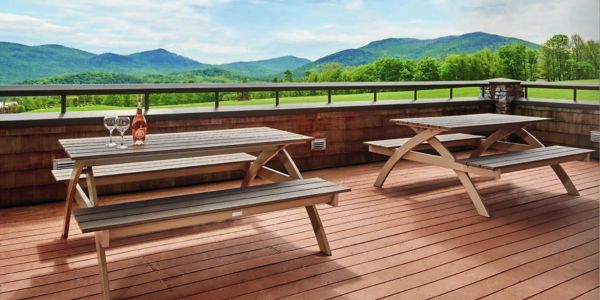 Wooden picnic tables on a deck with mountain views and drinks.