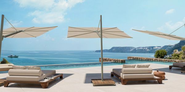 Luxury poolside loungers with umbrellas overlooking the ocean and cliffs.