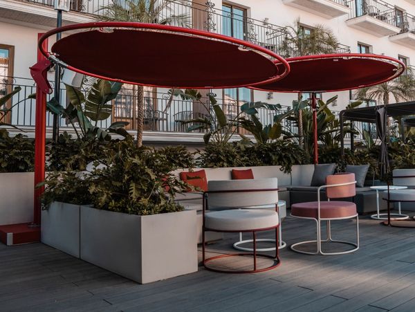 Modern outdoor seating area with red circular canopies and pastel chairs.