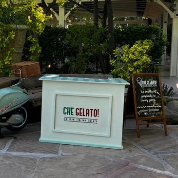 Outdoor gelato stand with vibrant greenery.
