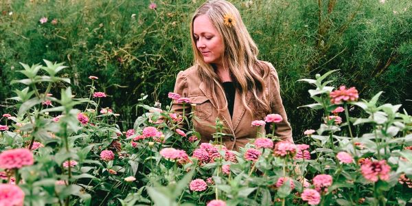 Woman admiring pink flowers in a garden.