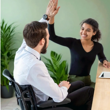 Young woman seated giving a high five to a young man in a wheelchair. Credit: Freepix