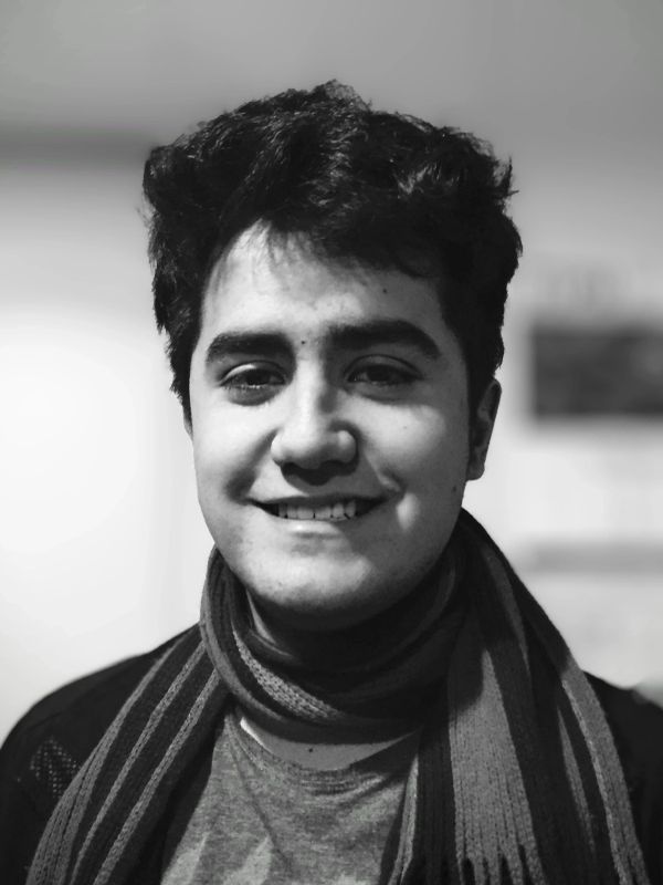 Joven sonriente con bufanda en blanco y negro.