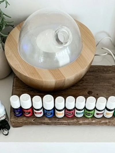 A wooden essential oil diffuser with a glass top and multiple essential oil bottles lined up.
