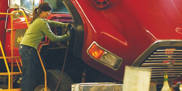 Woman servicing work truck with automotive supplies