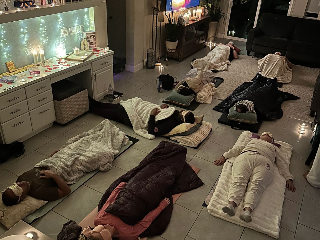 People lying on mats and blankets in a cozy room.