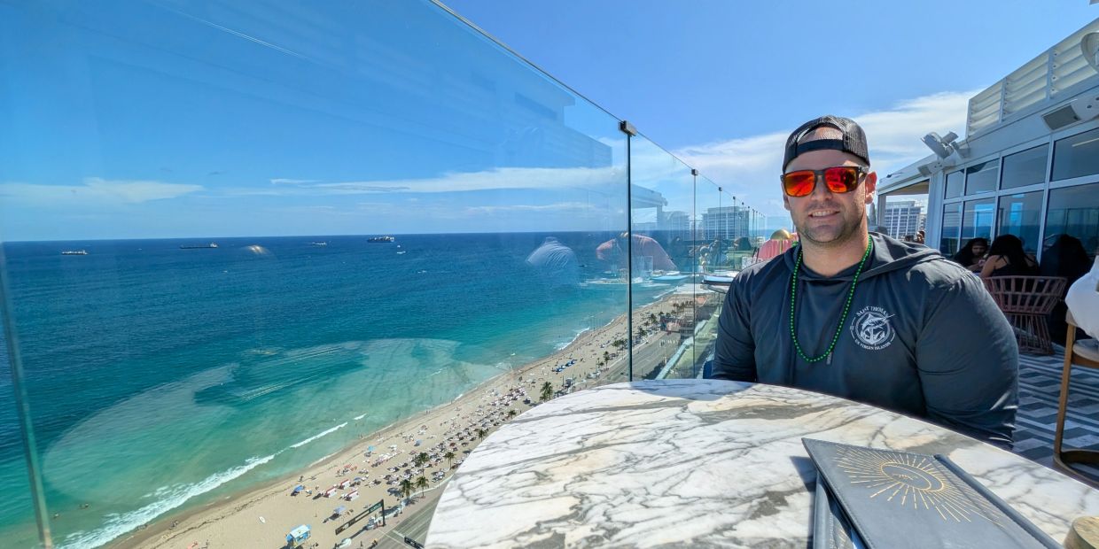 Man sitting at a rooftop restaurant with ocean view.