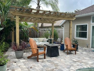 Cozy backyard seating area with wooden pergola and Adirondack chairs.