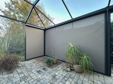 A screened patio with potted plants and a mesh enclosure.