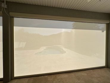 View of an outdoor pool through a translucent window screen.