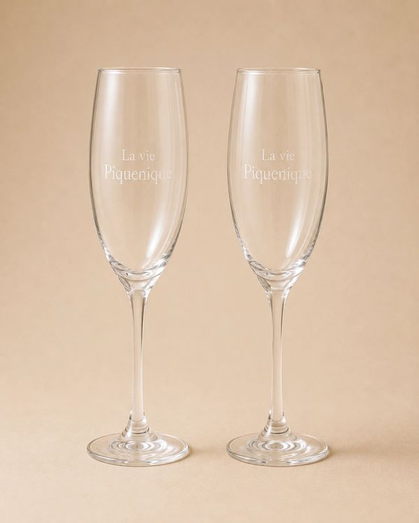 Two clear champagne flutes with "La vie Piquenique" etched on them.