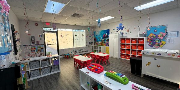 Bright and colorful ocean-themed preschool classroom with decorations and small tables.