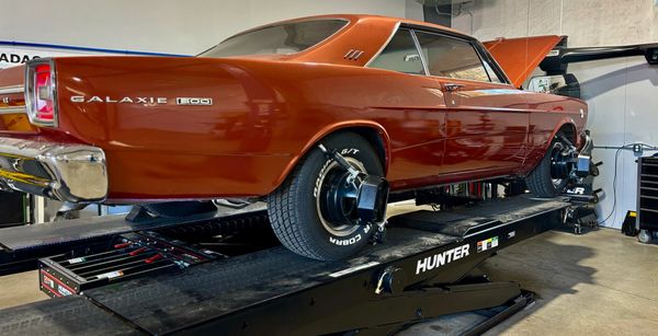 Classic orange Ford Galaxie 500 car on a Hunter alignment machine in a garage.