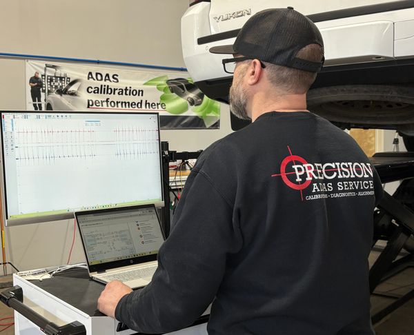 Technician calibrates ADAS using computer software in a workshop.