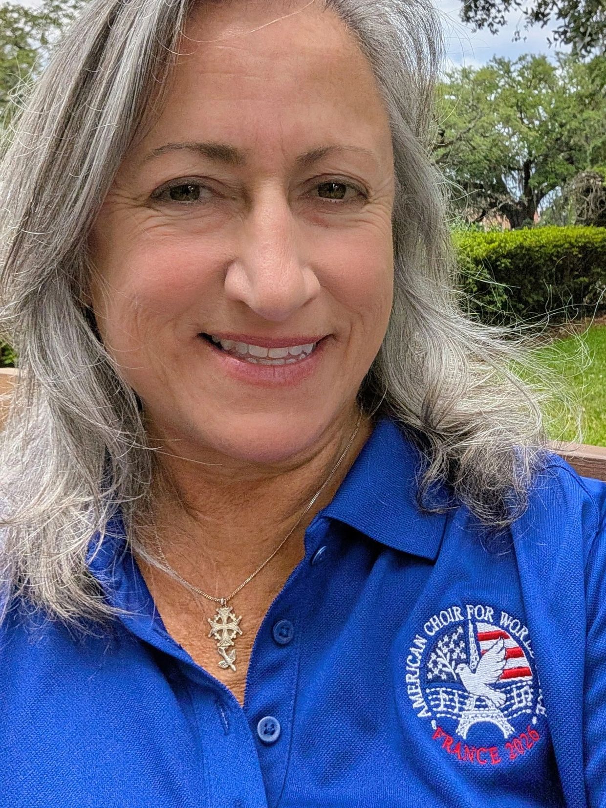 Smiling woman in blue polo shirt with embroidered logo.