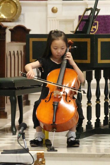 Young girl playing cello during a performance.