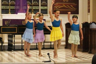 Four young girls performing a dance in a church.