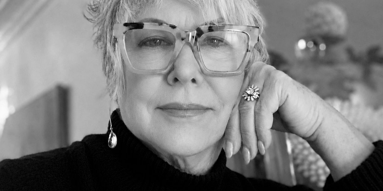 Close-up black and white portrait of a woman with glasses and jewelry.