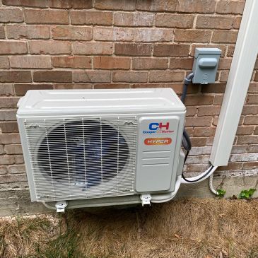 Outdoor air conditioning unit mounted on a brick wall.