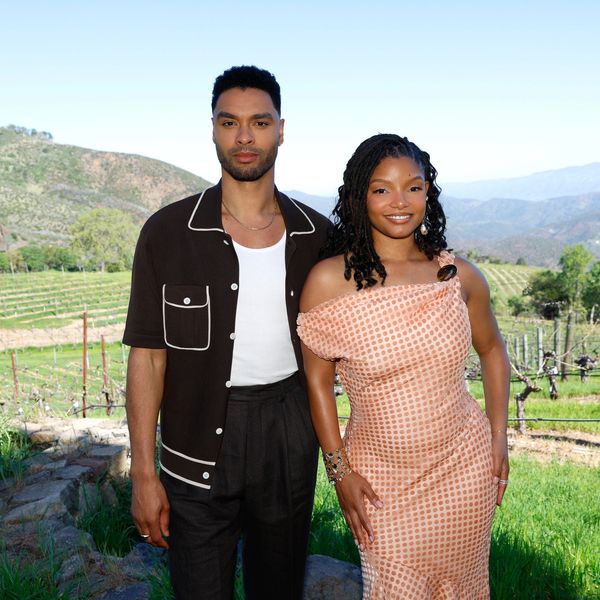 A stylish couple posing outdoors in a scenic vineyard setting.