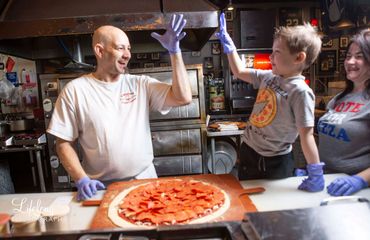 Chef high-5's son after pizza is built. Commercial photo shoot in Snohomish, WA