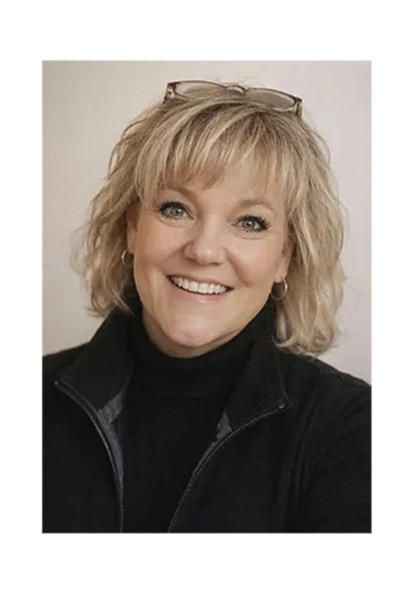 Image of Amy Grove smiling in a black turtleneck and vest.  She has glasses on her head.
