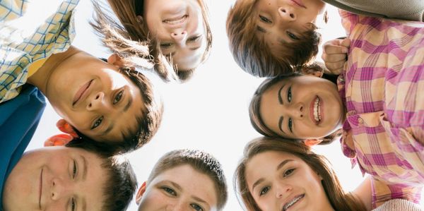 Image of seven children in a circle looking down towards the camera