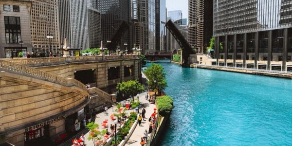 Open bridge over a vibrant river in a city with outdoor seating along the water.