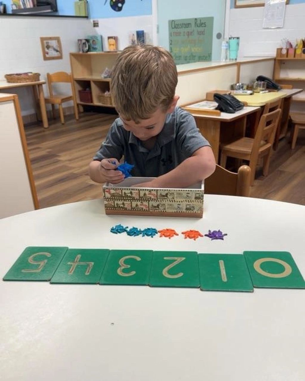 A young boy playing with colorful star-shaped toys and number cards in a classroom.