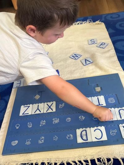 Niño jugando con letras y símbolos en un tapete.