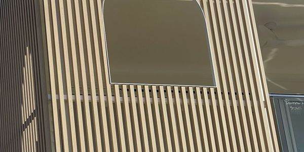 Modern building facade with vertical wooden slats and a rectangular window.