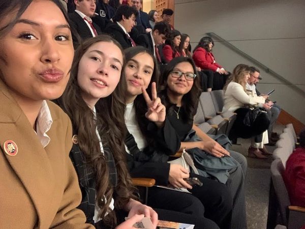 Four young women posing for a selfie in an auditorium.