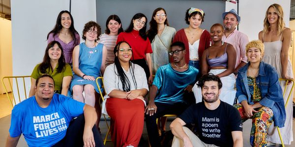 A diverse group of people smiling together in a casual indoor setting.