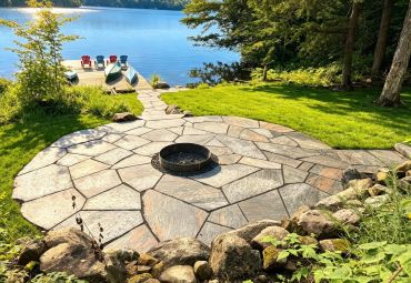 Stone patio with fire pit by a lake dock.
