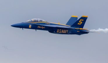 U.S. Navy Blue Angels jet in flight with number 5 on tail.