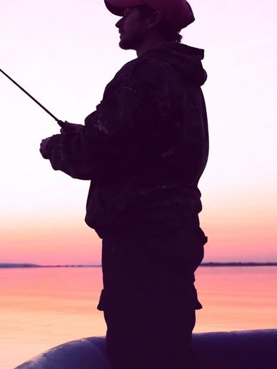 Silhouette of a man fishing at sunset by the lake.