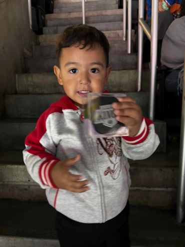 Smiling young boy holding a card inside a stairwell.