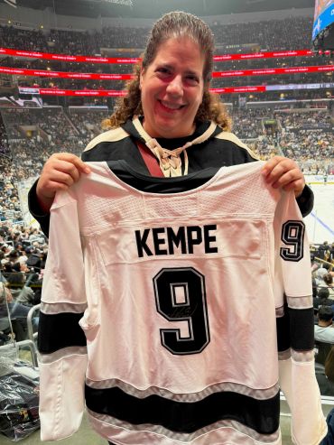 Fan holding Kempe hockey jersey at game.