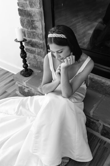 a black and white photograph of a bride sitting on the stone fireplace at the Manor at Mountain View