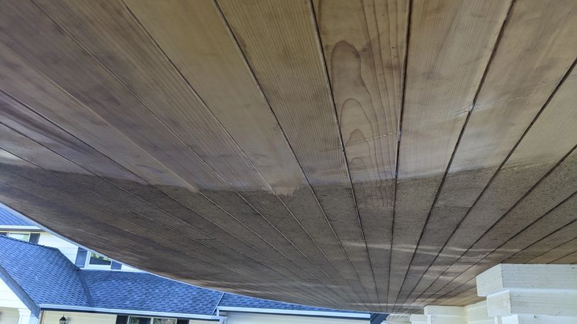 Wooden ceiling with half cleaned and half dirty sections under a roof.