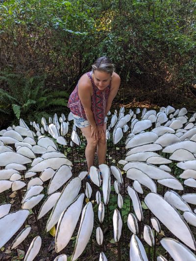 Woman observing a unique outdoor art installation resembling white leaves.