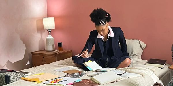 a woman sit on the bed with reading on the book and writing a notes