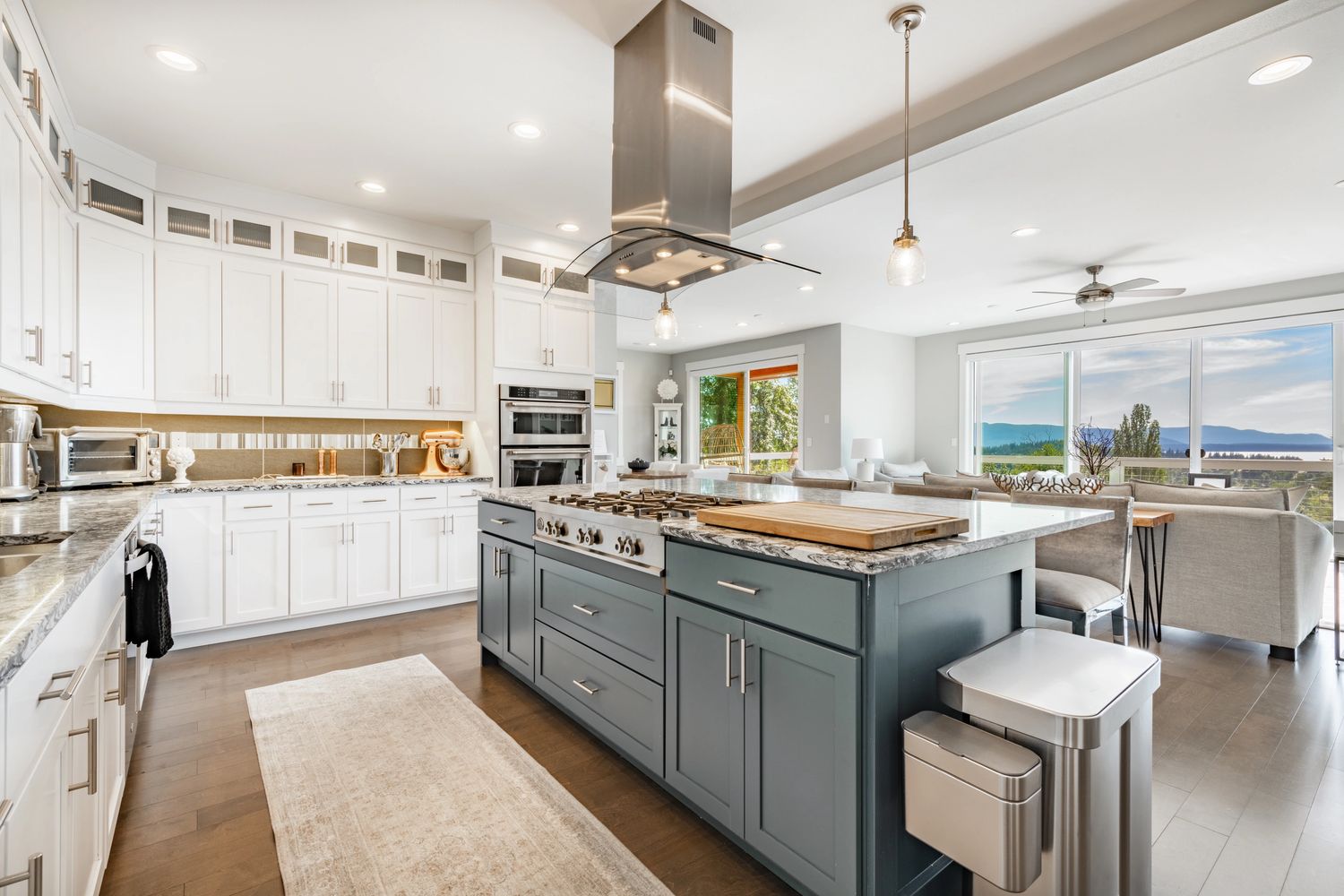 Bright modern kitchen with large island and scenic view.