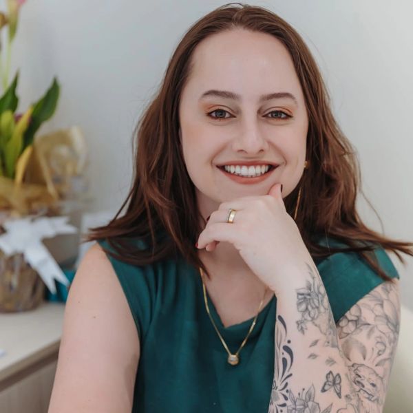 Mulher sorridente com tatuagens no braço.